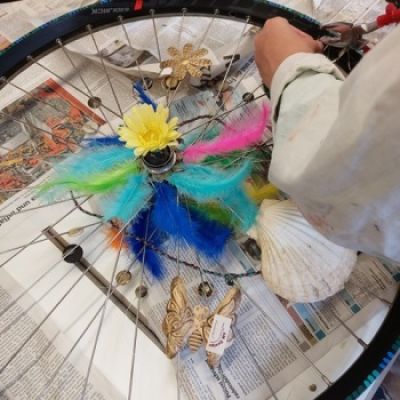 Jugendliche verziert Fahrradfelde mit bunten Materialien